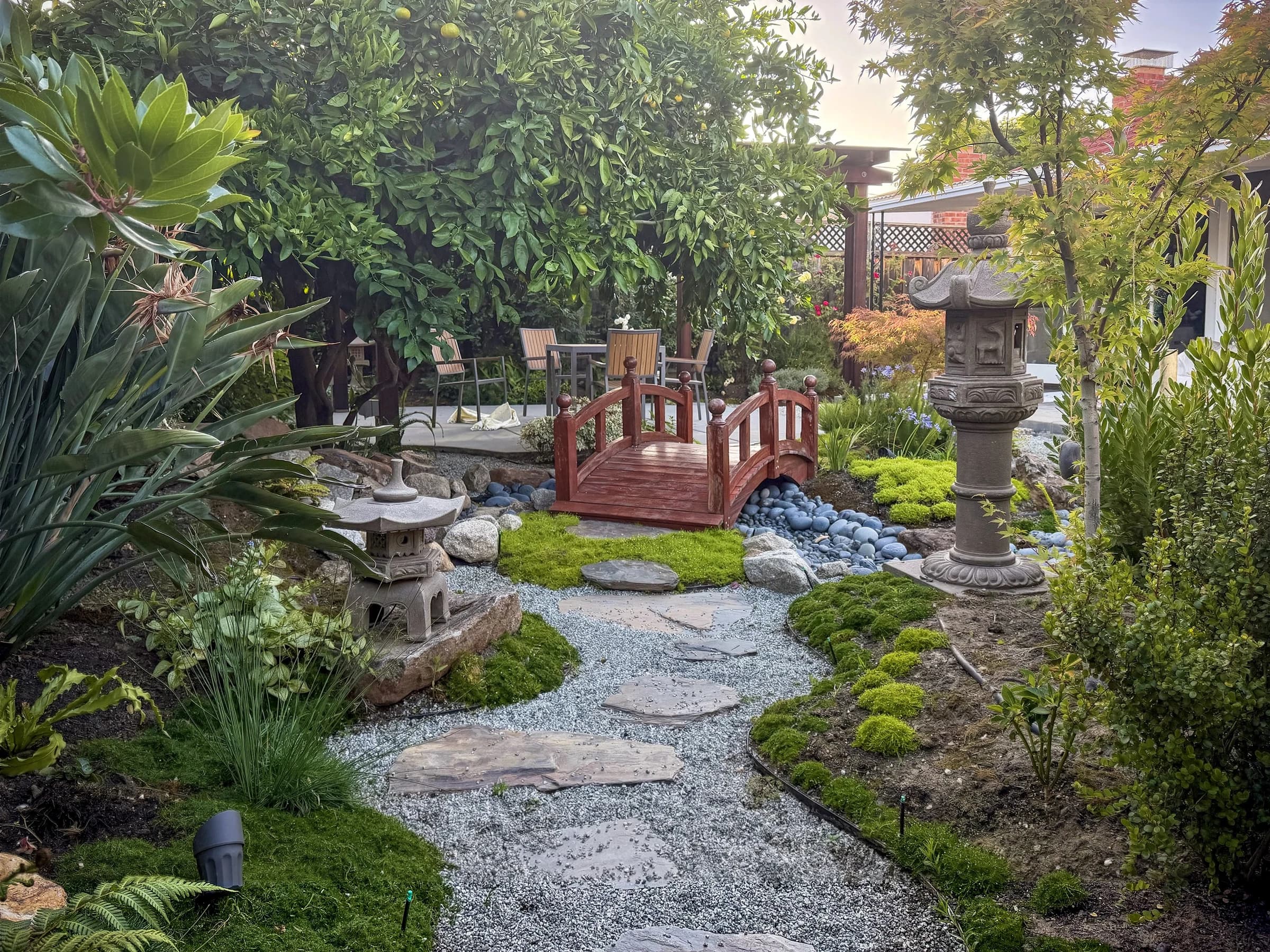 A timber bridge, stone, and layered planting in a completed garden by Peilin Li